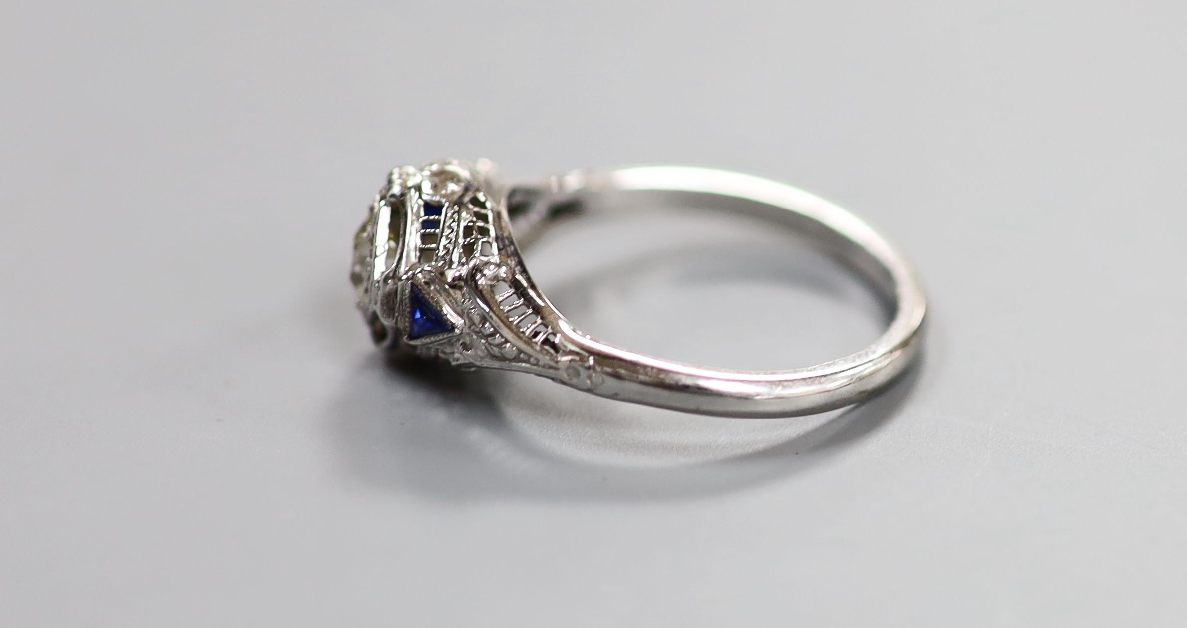 A 18ct white metal and single stone diamond ring, with triangular cut blue stone set shoulders, size P, gross weight 3.2 grams.